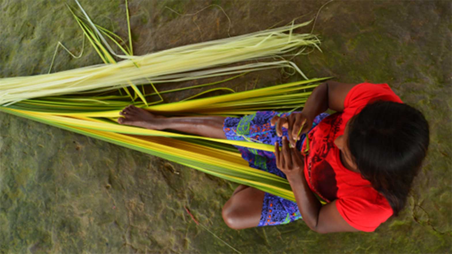 a person sitting creating something with reeds